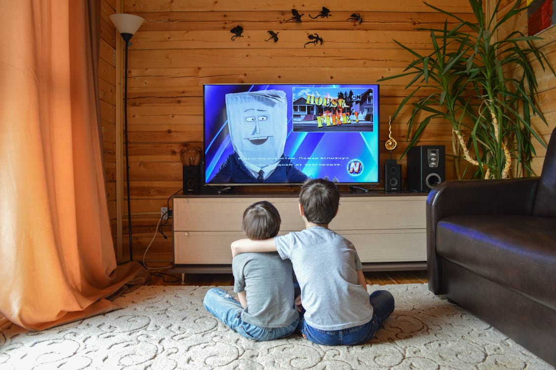 Children watching TV at home using one of the best streaming services for kids.
