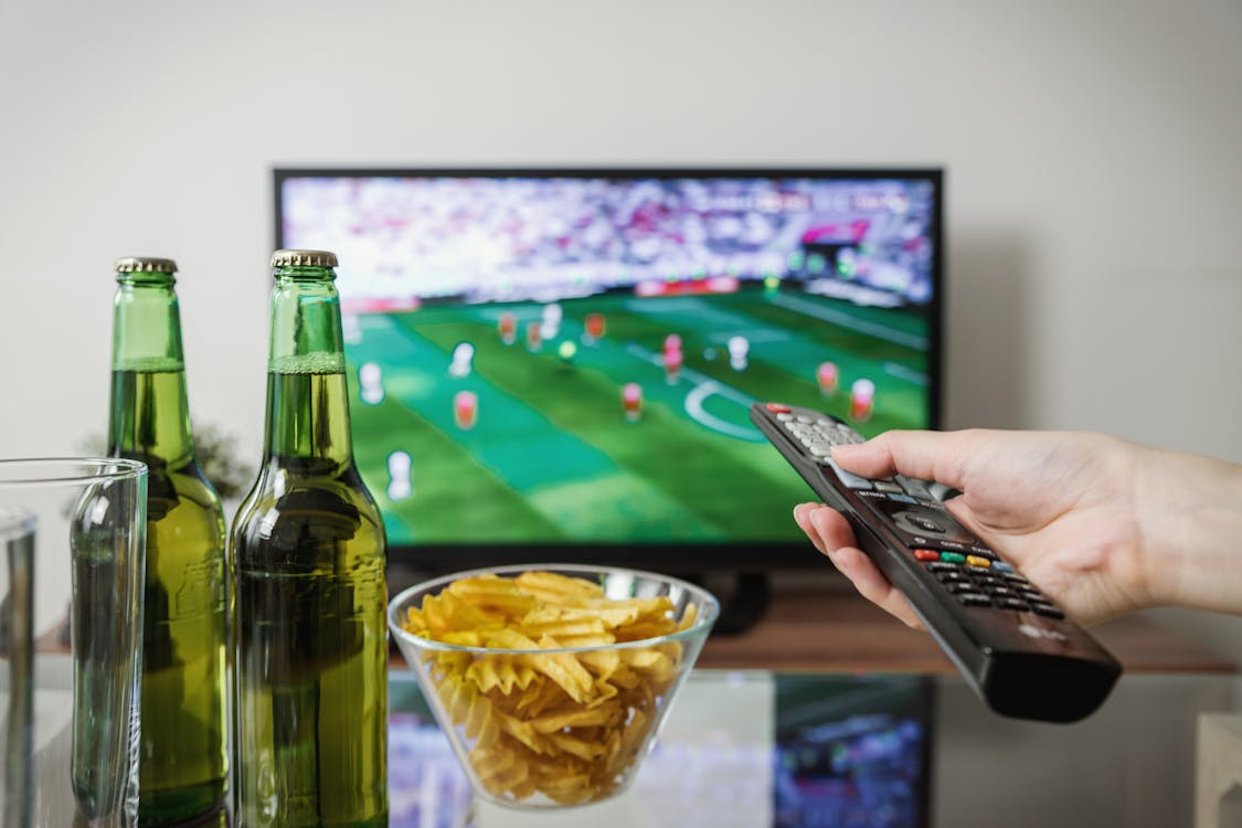 Person watching a live game on TV while comparing the best streaming services for sports.