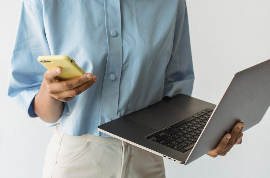 Using a phone and laptop while comparing the best unlimited phone plans for data and hotspot use.