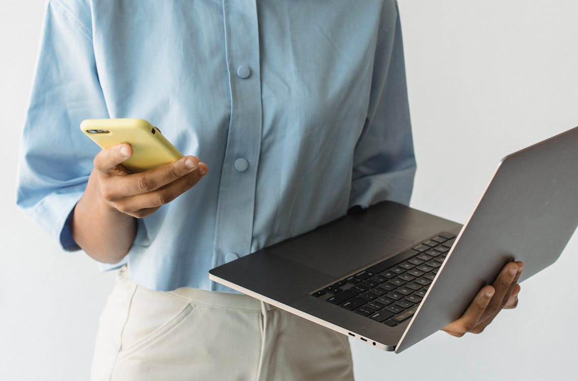 Using a phone and laptop while comparing the best unlimited phone plans for data and hotspot use.