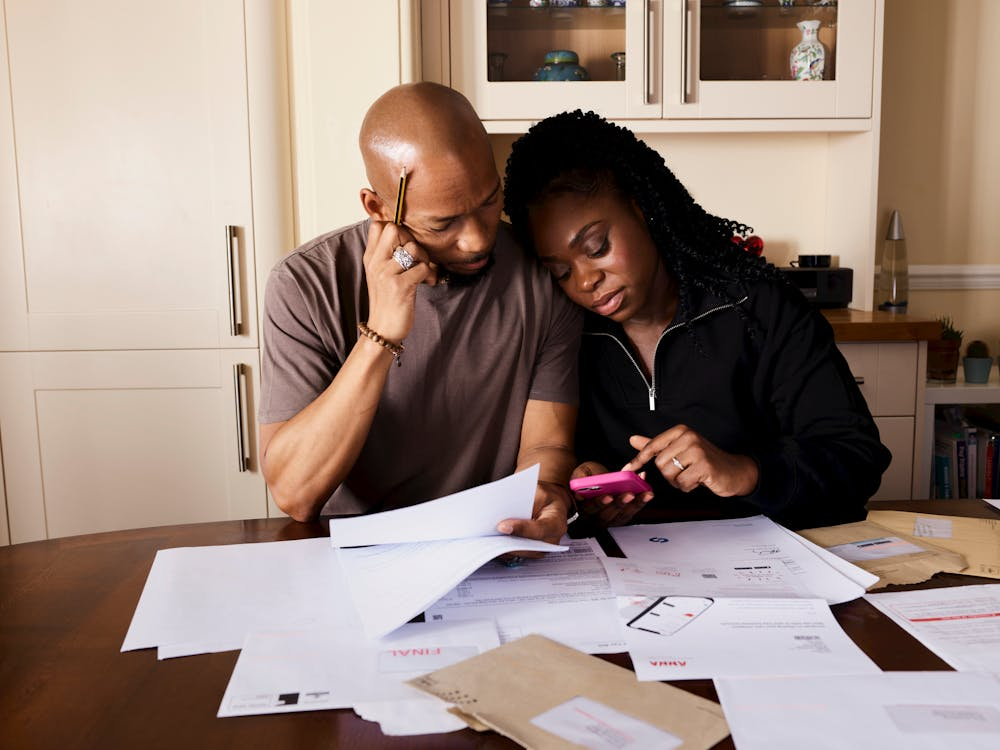 Couple reviewing bills while comparing family phone plans for shared wireless savings.