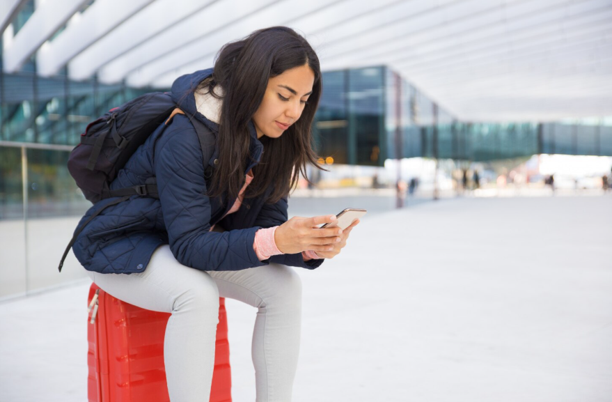 Traveler using a smartphone abroad while comparing the best international phone plans for staying connected.
