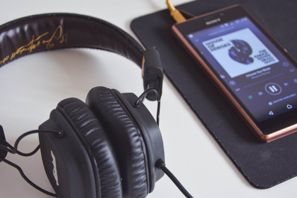 Best music streaming service shown with headphones and a mobile music player app.