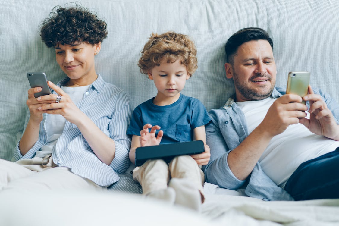 Family using multiple devices at home while comparing the best internet plans for streaming without buffering.
