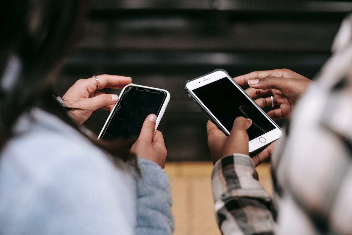 Prepaid vs postpaid phone plans compared by two people using smartphones.