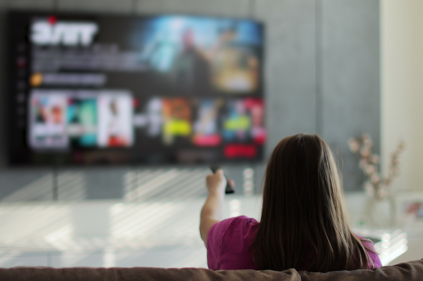 Smart TV vs streaming stick setup with a viewer browsing streaming apps on a large TV.