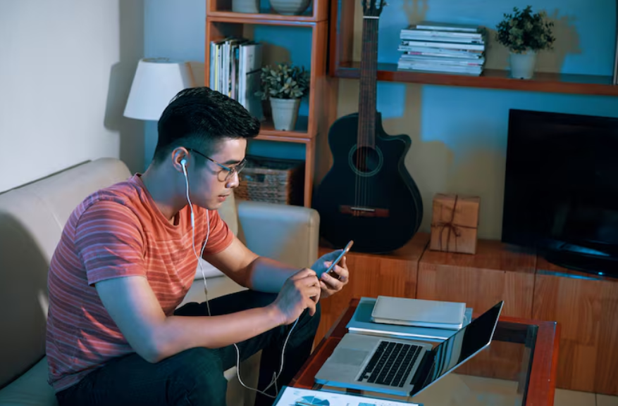 Person using phone and laptop at home while comparing the best phone plans for heavy data users.