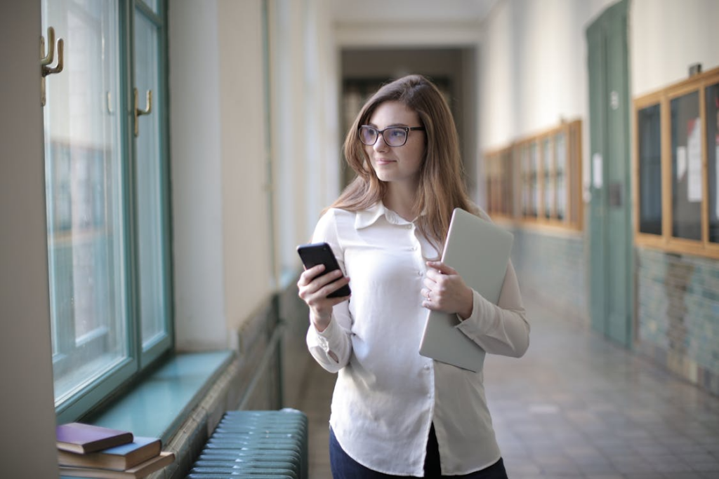 Student using a phone and laptop while comparing the best phone plans for students.