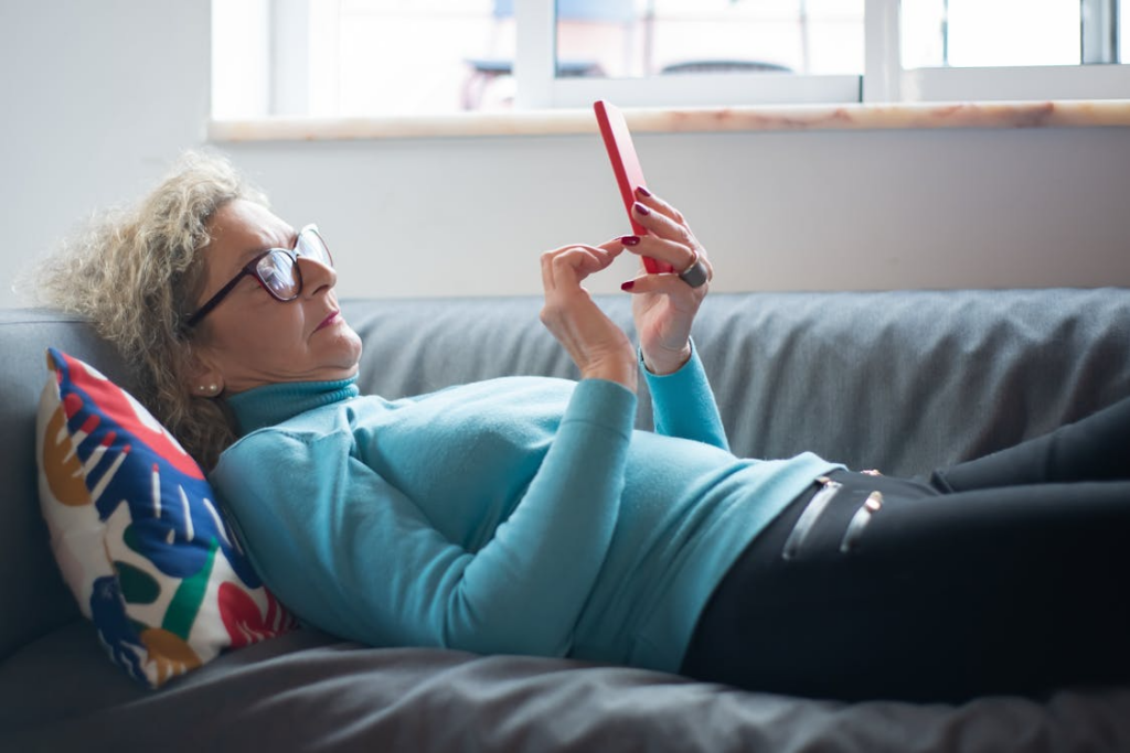 Senior using a smartphone at home while comparing the best senior phone plans for simple coverage.